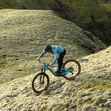 A woman rides a her bike through the rugged Icelandic countryside with a Thule Vital hydration pack.